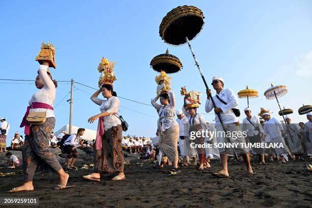 Balinese people walk to pray during the Melasti ceremony prayer at a beach in Denpasar, on Indonesia's resort island of Bali on March 8, 2024....