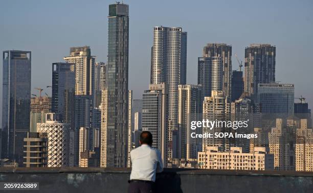 Man looks towards high rise buildings in Mumbai. High-rise buildings dominate the construction landscape, constituting approximately 77% of the...