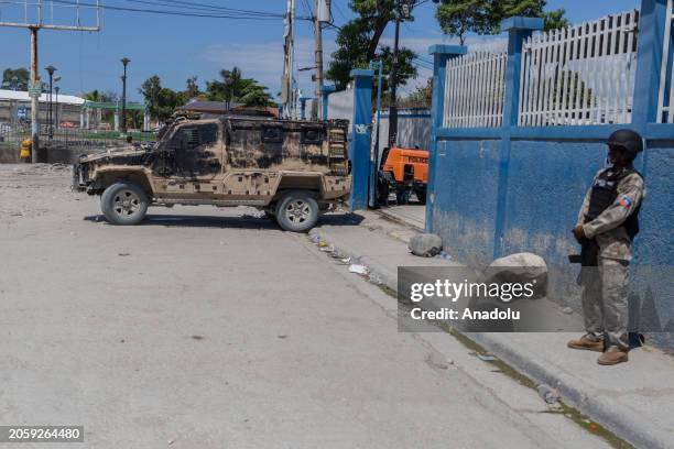 Police stands guard in front of the Brigade d'Intervention Motoris police base as a damaged armored police vehicle is seen behind while Haiti's...