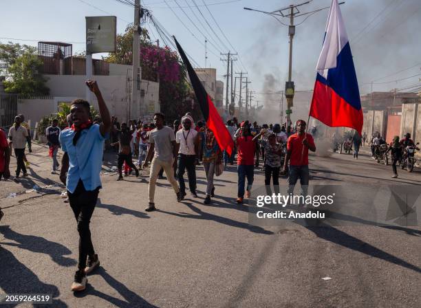 People, carrying Haitian flags, march during a demonstration demanding the resignation of Haitian Prime Minister Ariel Henry as Haiti's government...