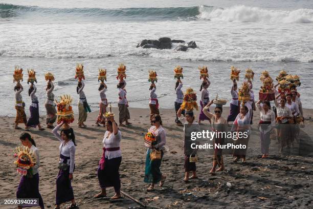 Balinese Hindu is carrying sacred ornaments while participating in the Melasti ceremony on Masceti Beach in Gianyar, Bali, Indonesia, on March 8,...