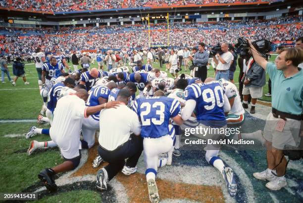 Players from the Indianapolis Colts and the Miami Dolphins kneel as a group following an NFL football game played on December 5, 1999 at Pro Player...