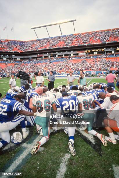 Players from the Indianapolis Colts and the Miami Dolphins kneel as a group following an NFL football game played on December 5, 1999 at Pro Player...