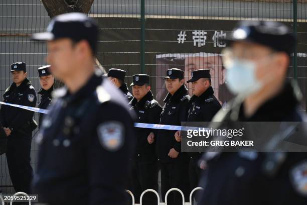 Police stand in a line to block the street leading to the Malaysia embassy during a gathering of relatives of passengers on board the missing...