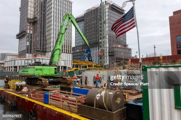 Work crew continues an environmental project on the Gowanus Canal in the rapidly gentrifying Brooklyn neighborhood of Gowanus where a new migrant...
