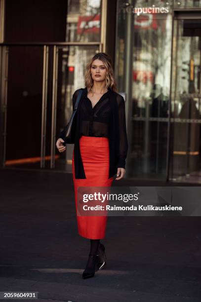 Chloe Lecareux is seen wearing a black transparent top, red skirt and black bag outside Zimmermann during the Womenswear Fall/Winter 2024/2025 as...