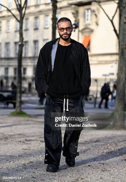 Ahmad Mohsen is seen wearing a black jacket, black shirt, black button pants and black shoes outside the Sacai show during the Womenswear Fall/Winter...