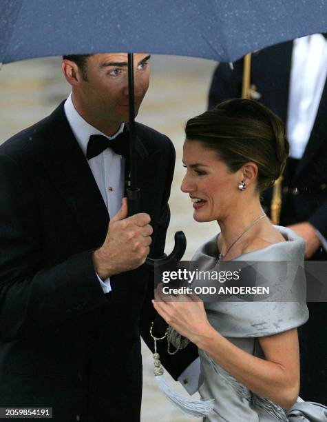 Spanish Crown Prince Felipe of Bourbon and his fiancee former journalist Letizia Ortiz take shelter under an umbrella as they arrive to an official...