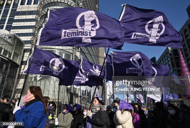 South Korean women carry flags reading "Feminist" as they march during a rally to mark International Women's Day in downtown Seoul on March 8, 2024.