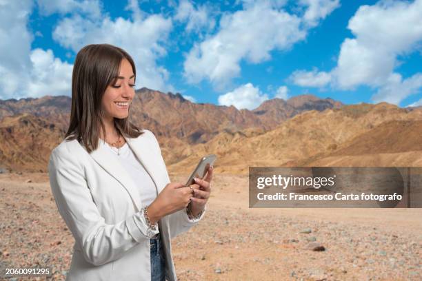 smiling woman using smart phone  on vacation in the sinai desert.egypt - sinai egypt stock pictures, royalty-free photos & images