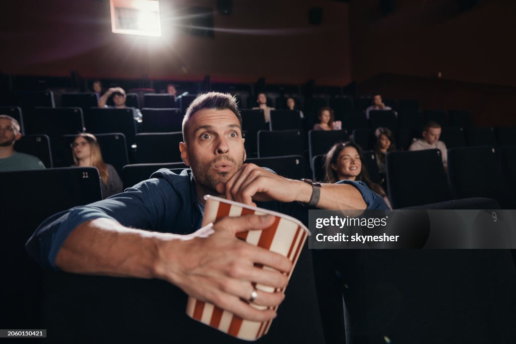 Surprised man watching a movie in cinema.
