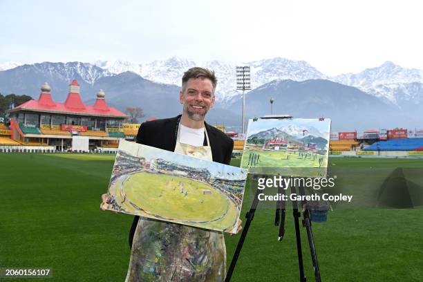 Artist Andy Brown with his paintings at Himachal Pradesh Cricket Association Stadium on March 05, 2024 in Dharamsala, India.