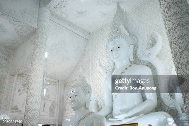 beautiful white buddha statue inside ordination hall of wat huay pla kang temple in chiang rai province of thailand. - kang stock pictures, royalty-free photos & images
