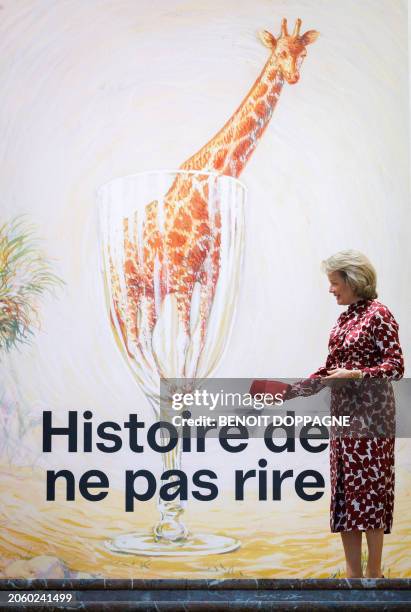 Queen Mathilde of Belgium stands next to the official poster of the exhibition 'Histoire de ne pas rire, Surrealism in Belgium' at Bozar museum in...