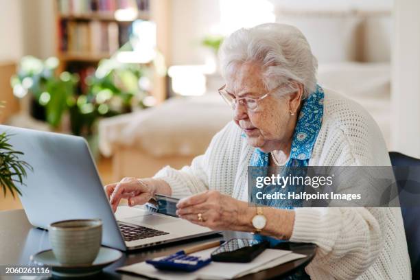 senior woman paying with debit card online, using internet banking and payment gateway. elderly woman working on laptop, shopping online, risk of frauds and hoax for elderly people. - bank fraud stock pictures, royalty-free photos & images