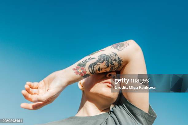 woman covering her eyes with her arm with tattoo - face arms stock pictures, royalty-free photos & images