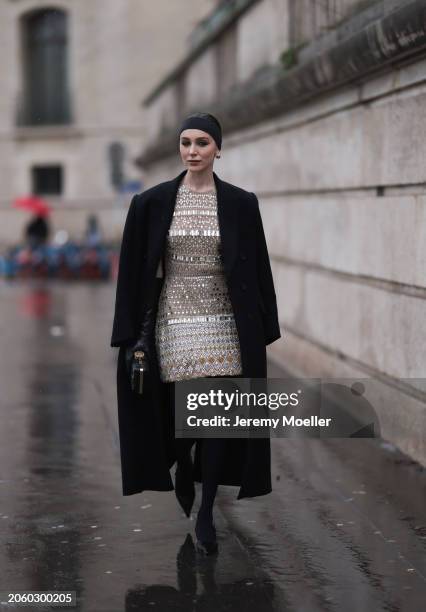 Mary Leest seen wearing gold earrings, black hair band, black oversized wool long coat, gold shiny embroidered midi dress with details and patterns,...