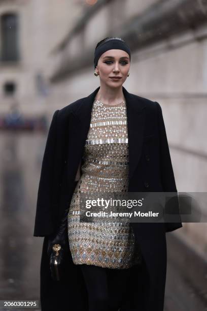 Mary Leest seen wearing gold earrings, black hair band, black oversized wool long coat, gold shiny embroidered midi dress with details and patterns,...