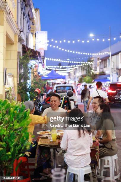 a diverse group of friends delighting in tasty street food adventures together. - penang state stock pictures, royalty-free photos & images