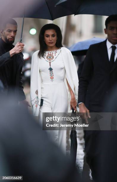 Jessica Aïdi Verratti seen wearing gold earrings, a white with colorful pearl embroidered long cape jumpsuit and a black umbrella, before Elie Saab,...