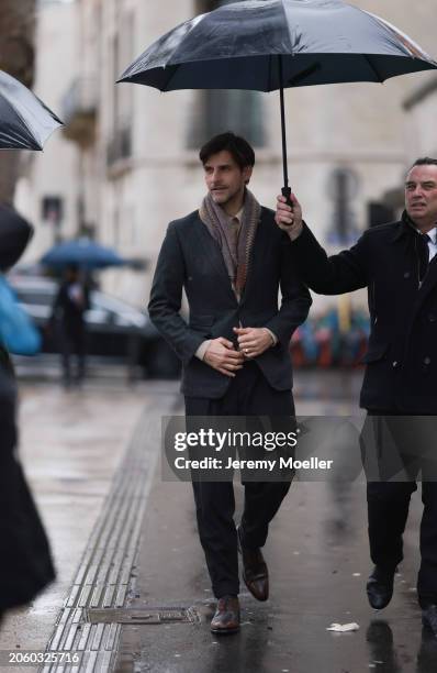 Johannes Huebl seen wearing a beige buttoned shirt, colorful pattern scarf, grey blazer jacket, black long suit pants and brown leather shoes, before...