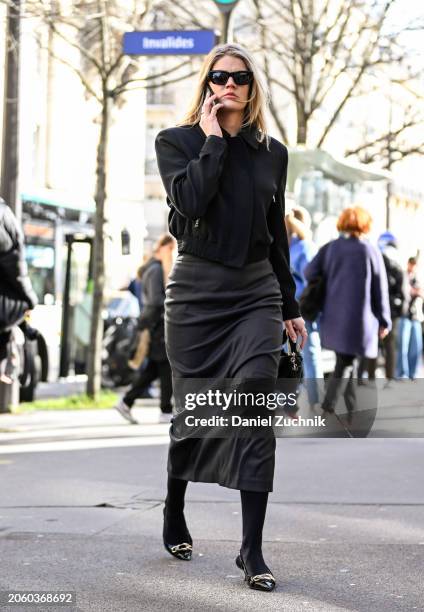 Guest is seen wearing a black top, gray skirt, black and silver shoes and black sunglasses outside the Sacai show during the Womenswear Fall/Winter...