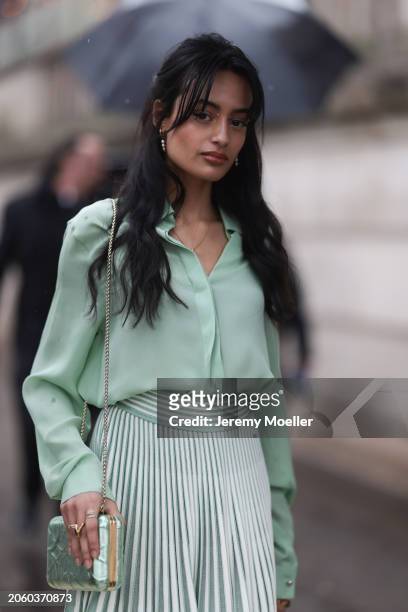 Sabrina Bahsoon seen wearing gold / pearl earrings, gold necklace, pastel green buttoned silk shirt, pastel green / white striped pleated midi skirt...