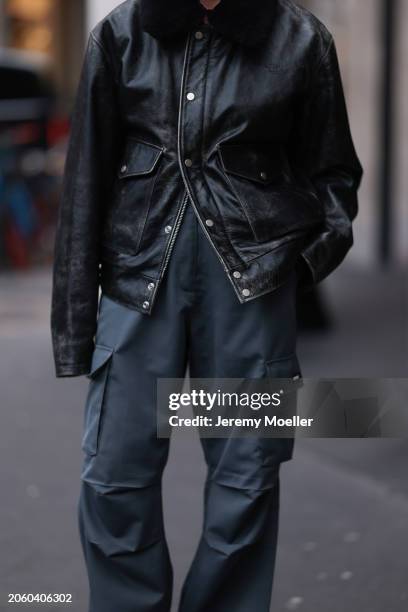 Guest seen wearing Diesel black oversized leather jacket with black fake fur collar, Coperni grey cargo pants, outside Vetements, during the...