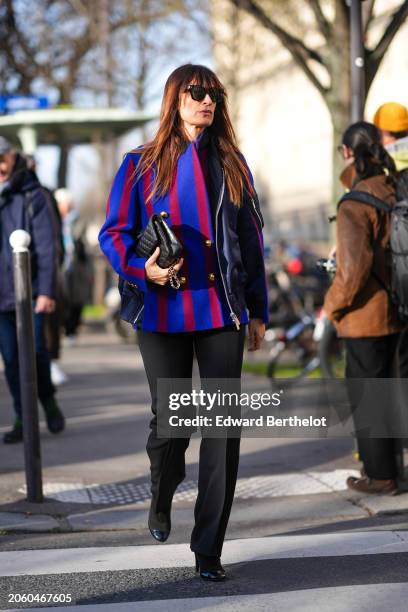 Caroline de Maigret wears a red and blue striped military jacket with golden buttons, a Chanel bag, black flared pants, high heels leather boots,...