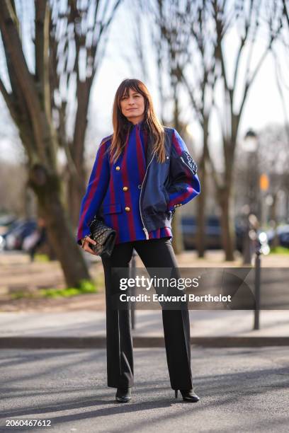 Caroline de Maigret wears a red and blue striped military jacket with golden buttons, a Chanel bag, black flared pants, high heels leather boots,...