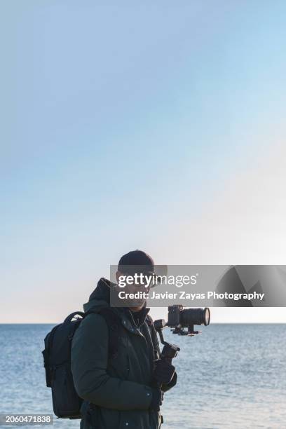 videographer operating camera outdoors on the beach - camera operator stock pictures, royalty-free photos & images