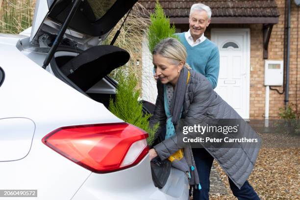 mature couple unloading plants from a car boot - veículo com carroçaria de dois volumes com três ou cinco portas imagens e fotografias de stock
