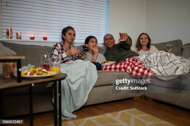 family enjoying a movie together - couple pyjamas night stock pictures, royalty-free photos & images