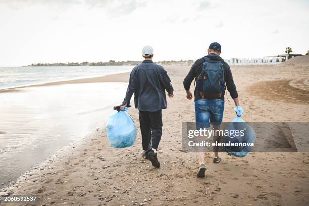 des hommes ramassent des ordures sur la plage - activité agricole photos et images de collection