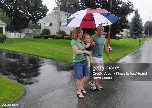 Times Union staff photo by Lori Van Buren -- Bill Heiserman holds an umbrella for Theresa DiMarino and her daughter Emily, age 2, as he walks them to...
