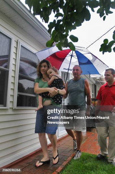 Times Union staff photo by Lori Van Buren -- Bill Heiserman holds an umbrella for Theresa DiMarino and her daughter Emily, age 2, as he walks them...