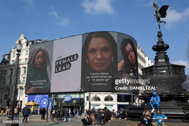 People walk by as pictures of British-Nigerian computer scientist Anne-Marie Imafidon, Guyanese-British business owner and social justice campaigner,...