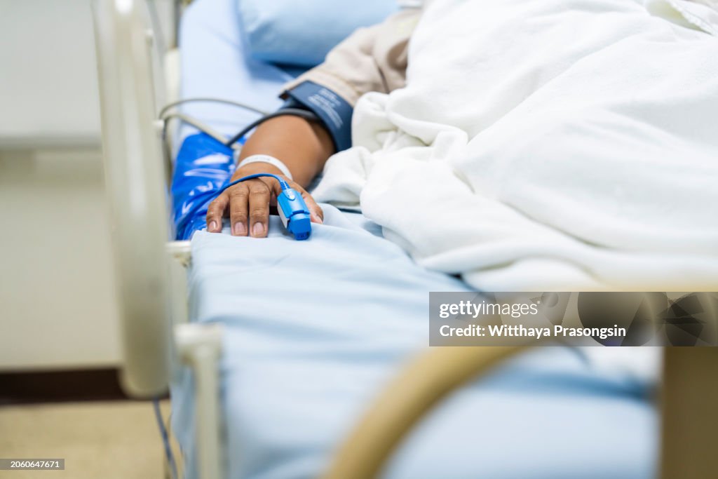 In the Hospital Sick Male Patient Sleeps on the Bed. Heart Rate Monitor Equipment is on His Finger.