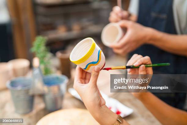 woman painting a cup in her small crafts workshop - potter stock pictures, royalty-free photos & images