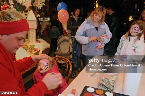 Haille Bates, age 2, of Saratoga Springs, gets her face painted by P.J. Duell, whiler her mom, Gail, and sister, Madison, age 8, watch at the...