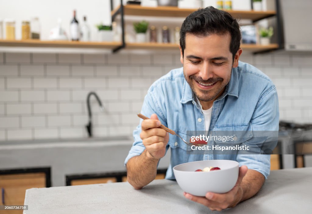 Man at home eating a bowl of fruits for breakfast