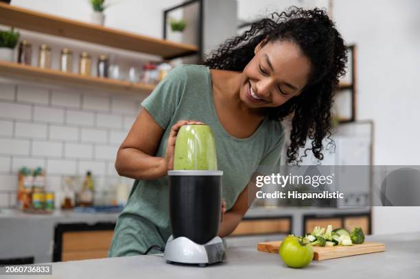 woman making a green smoothie at home - liquidiser stock pictures, royalty-free photos & images
