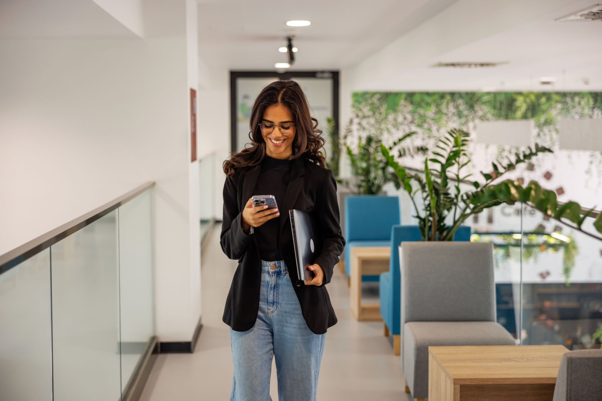 Successful young woman using smartphone while walking in business building Successful young woman using smartphone while walking in business building