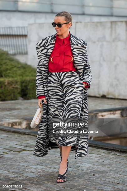 Nataly Osmann wears red shirt, black and white zebra print midi skirt with matching coat, black sandals, cream Stella McCartney bag, outside Stella...