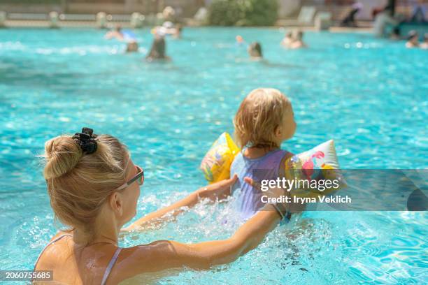 happy young mother swims and kisses  adorable baby in the pool or in the sea. - happy arab family on travel stockfoto's en -beelden