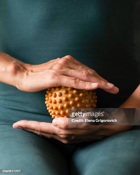 closeup of athletic woman in green body suit holding fascia ball for fascial massage and exercises - massage ball stock pictures, royalty-free photos & images