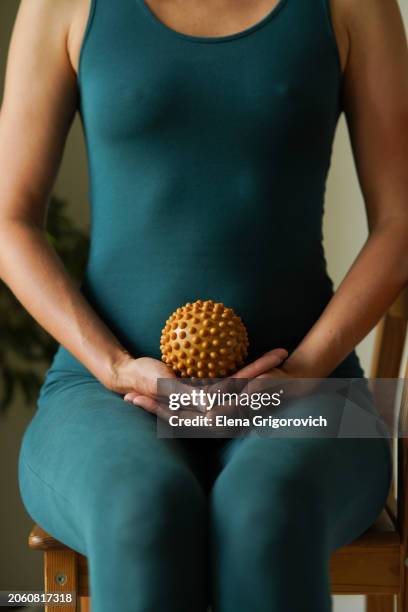 closeup of athletic woman in green body suit holding fascia ball for fascial massage and exercises - massage ball stock pictures, royalty-free photos & images