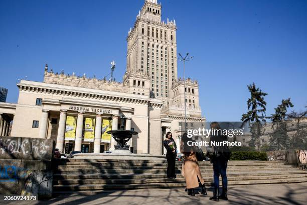 Women take phoyographes with flowers on International Women's Day in front of the landmark Palace of Culture and Science in the centre of Warsaw, the...