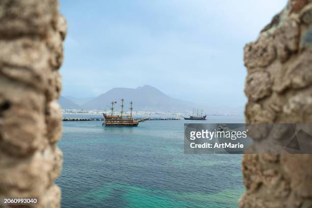 view to the sea and sailing ship through old walls of alanya fortress, turkey - alanya castle stock pictures, royalty-free photos & images