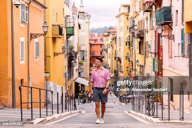 happy smiling man exploring colourful streets of nice old town, french riviera, france - the french riviera road stock-fotos und bilder